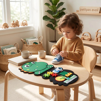 Enfant jouant avec un jouet éducatif en feutrine PetitPas Éveil en forme de dinosaure sur une table en bois